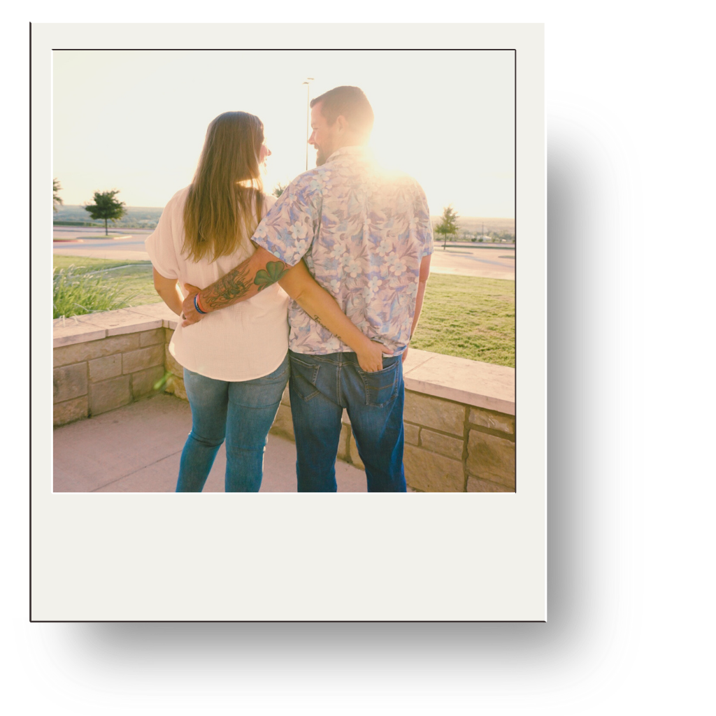 A couple standing outside during sunset, holding each other and smiling.