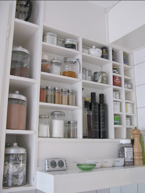 Organised kitchen pantry storage with open white shelving glass jars and containers for spices oils and dry goods clever storage solutions Melbourne