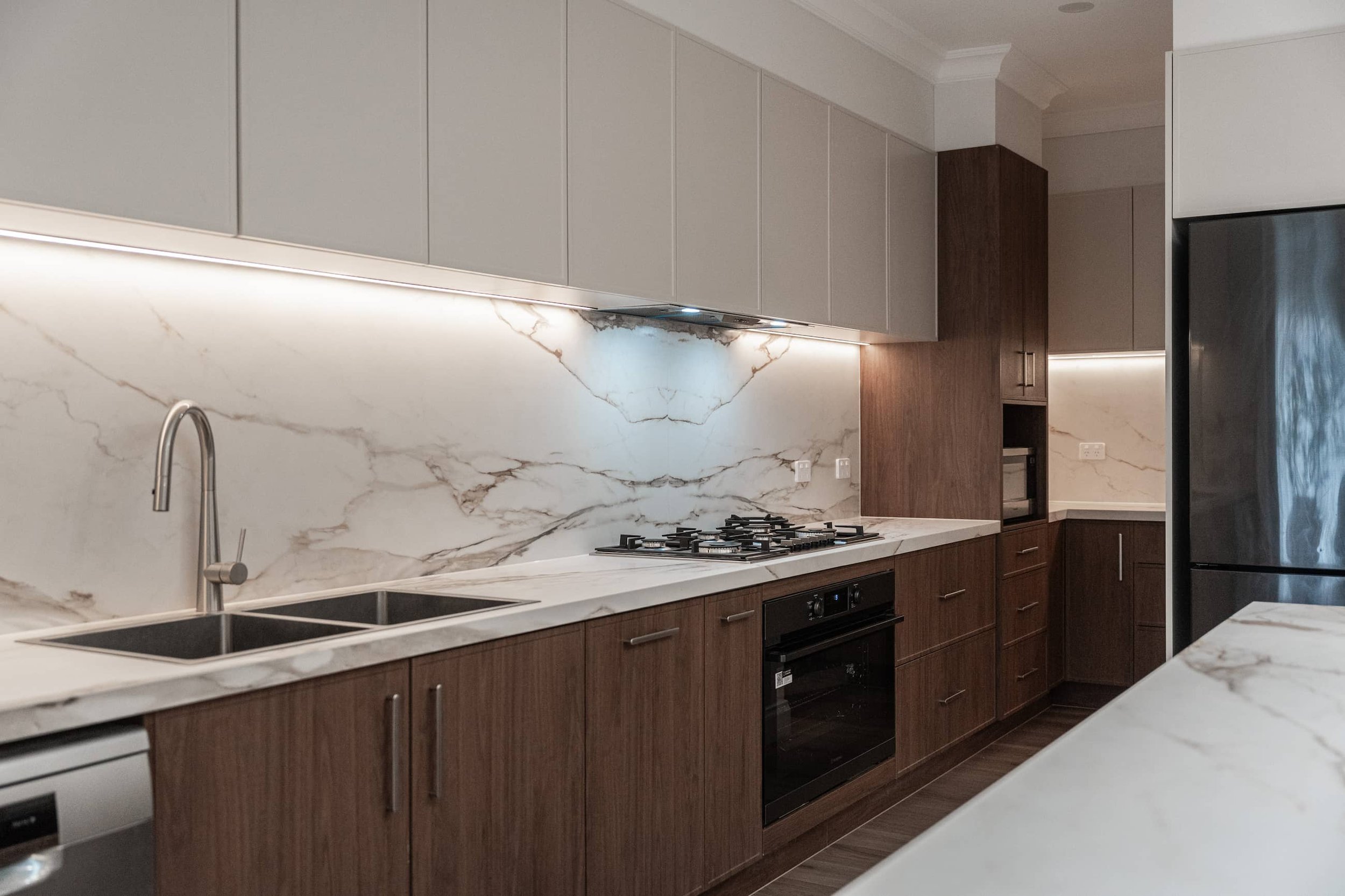 Modern kitchen with marble splashback timber cabinetry and under cabinet lighting