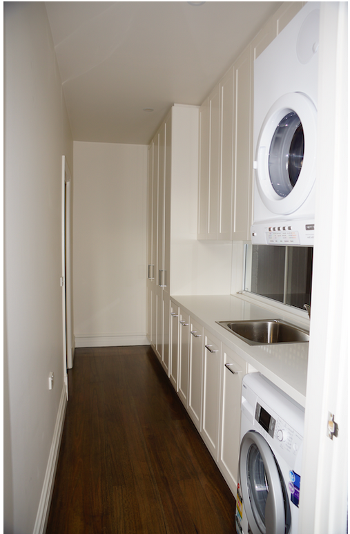Efficient laundry storage with floor to ceiling white cabinetry stacked washer dryer and bench space clever storage solutions Melbourne