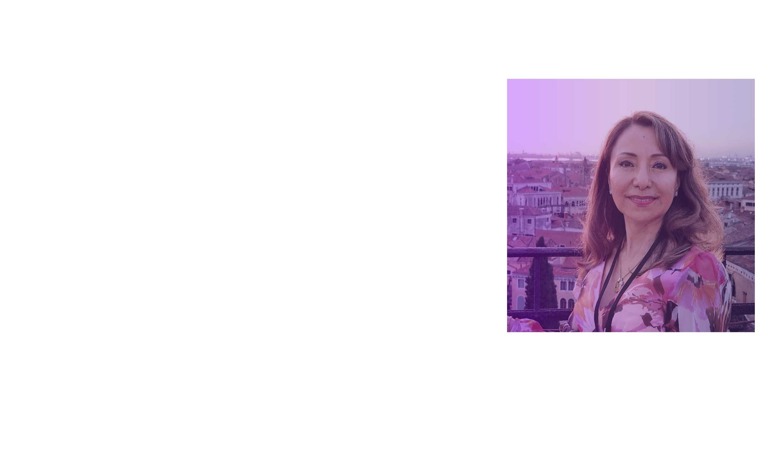 A woman smiling on a balcony with a cityscape in the background at sunset.