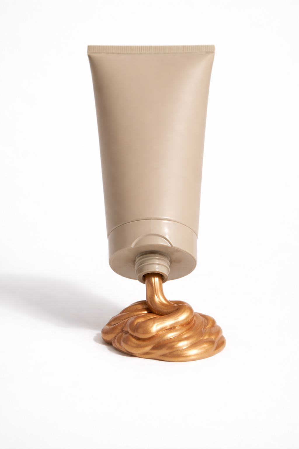 A beige tube of skincare or cosmetic product with copper-colored cream or lotion spilling out of the opening onto a white surface.