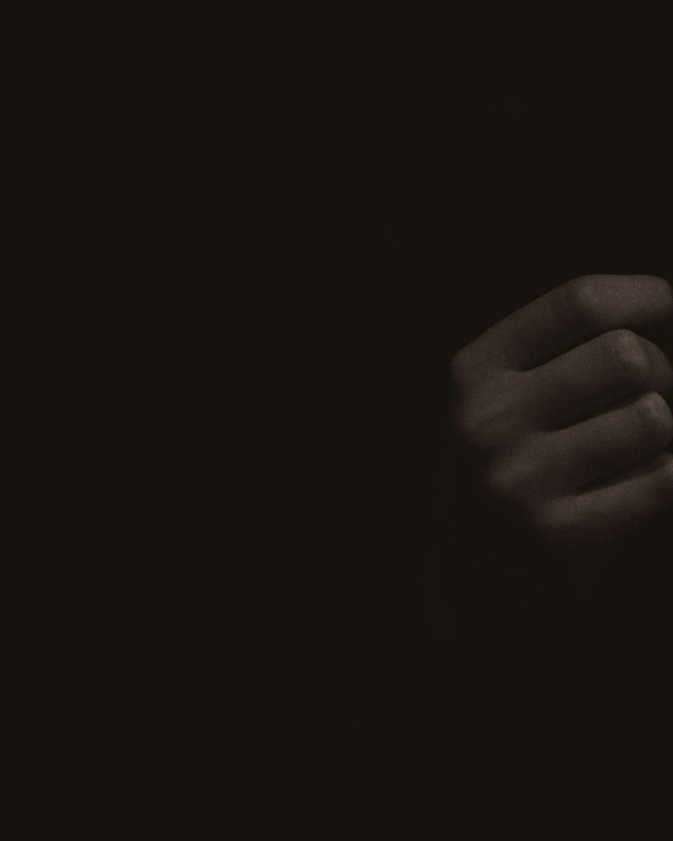 A hand partially visible against a dark background, with fingers gently curled.