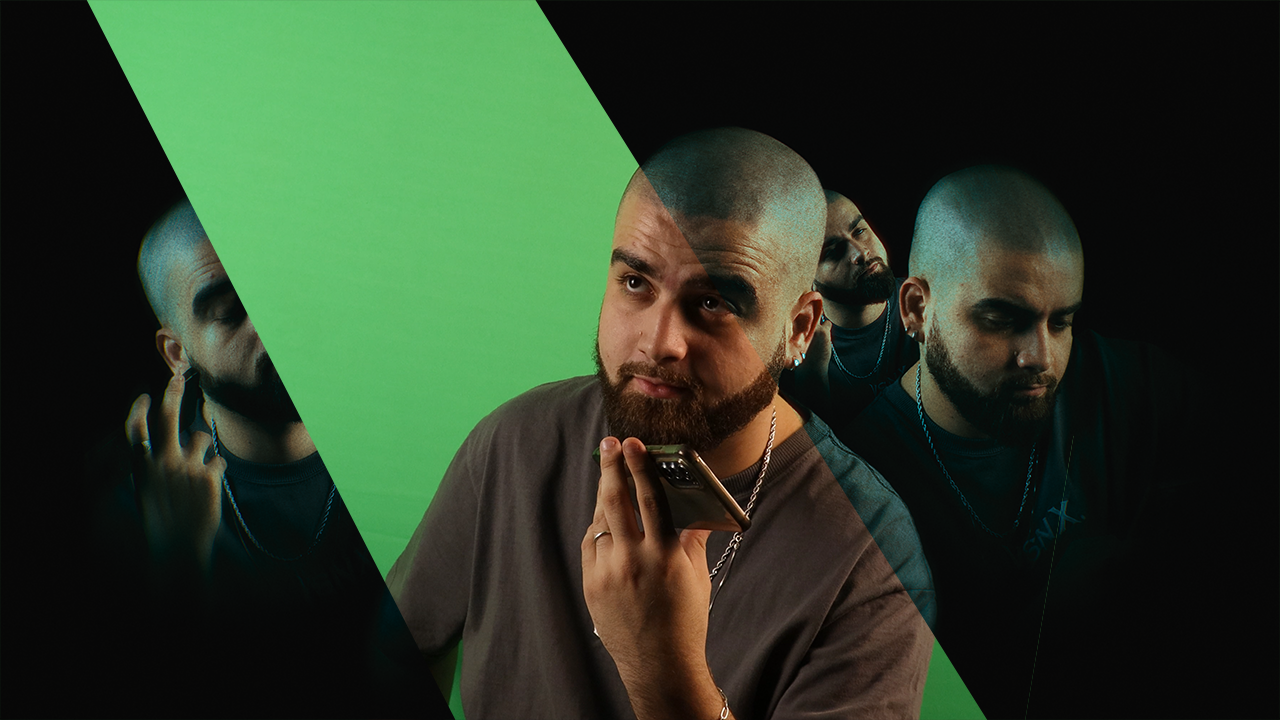 Homem com barba e cabeça raspada, segurando celular, com fundo dividido em preto, verde e falso preto, com reflexos de si mesmo em diferentes poses ao fundo.