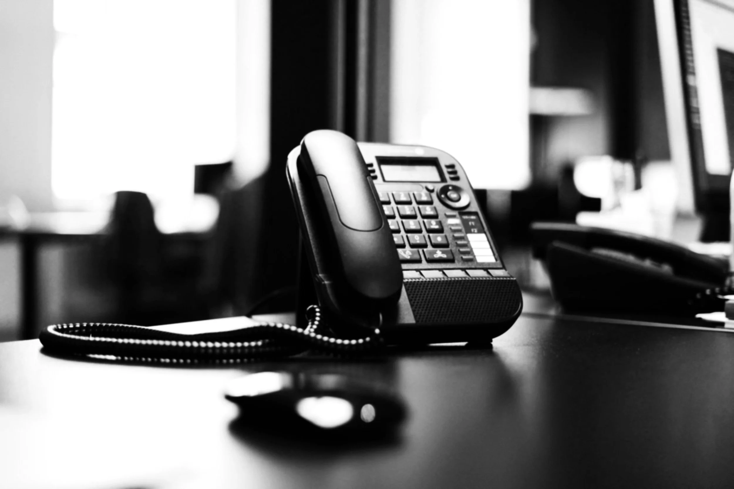 Telefone de escritório em uma mesa, em preto e branco.