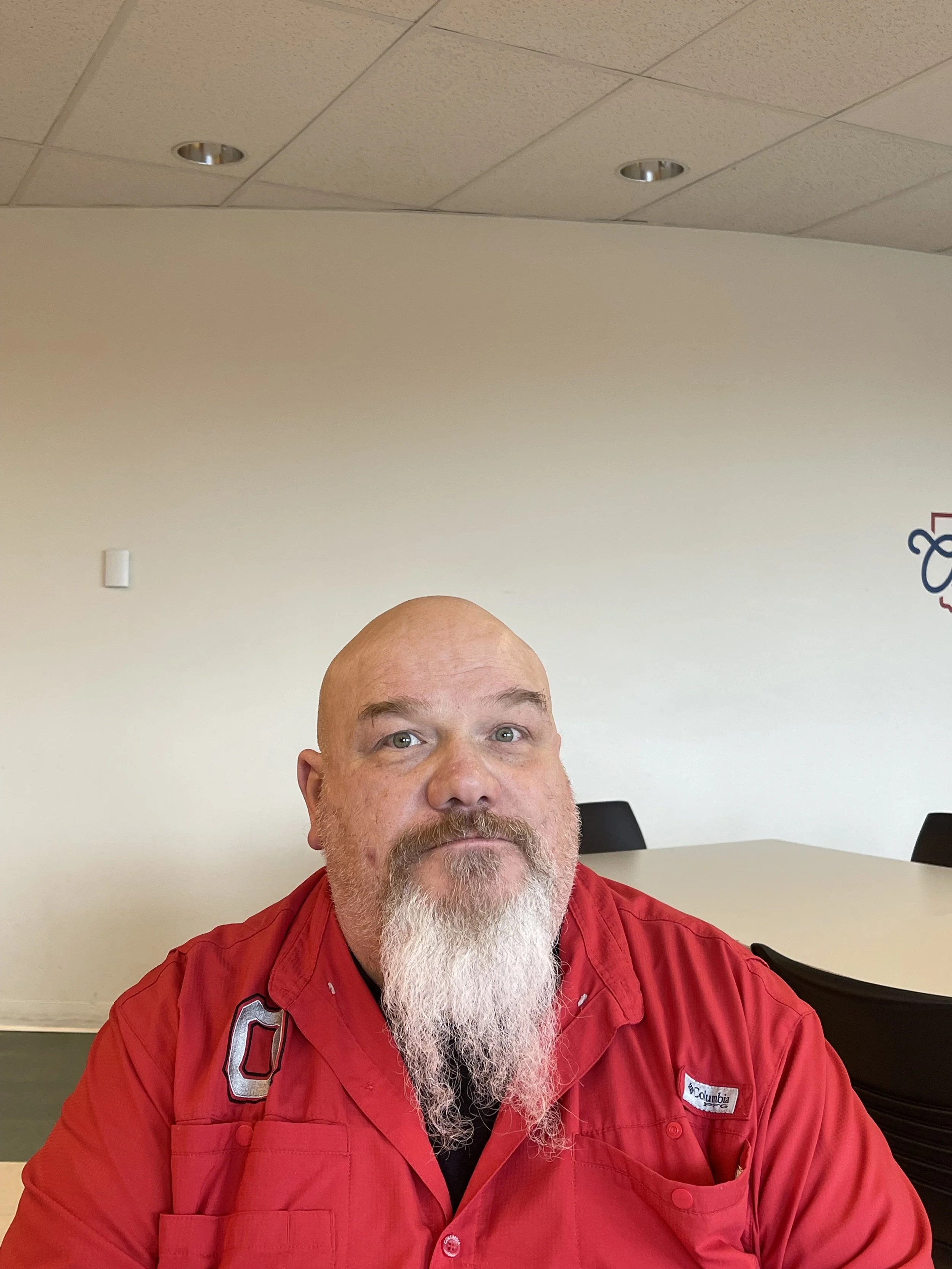 A man with a red collar shirt sitting down