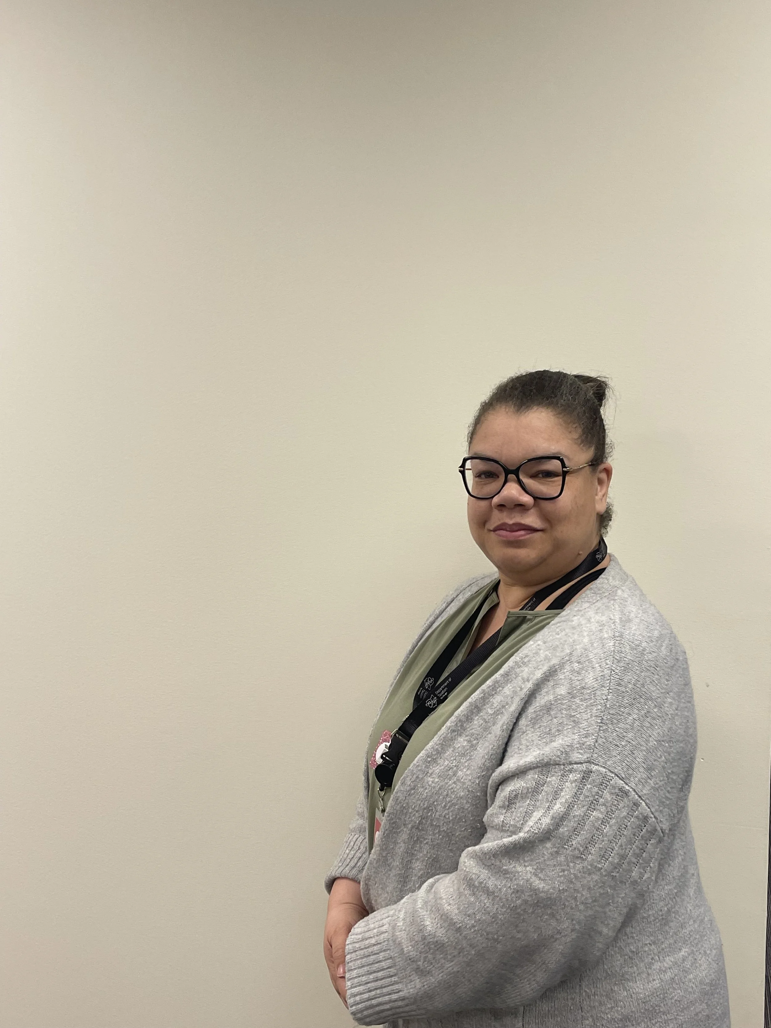 A woman standing and smiling in front of a white wall