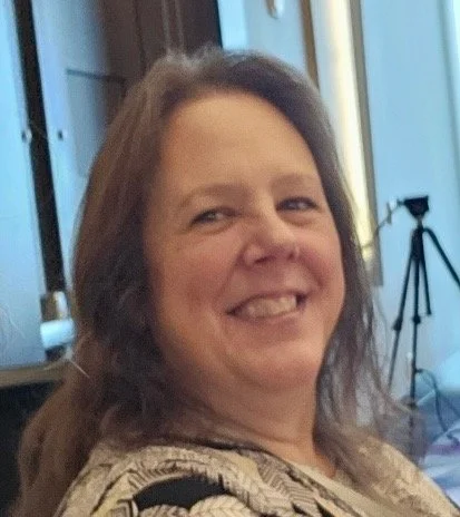 A woman smiling next to a camera