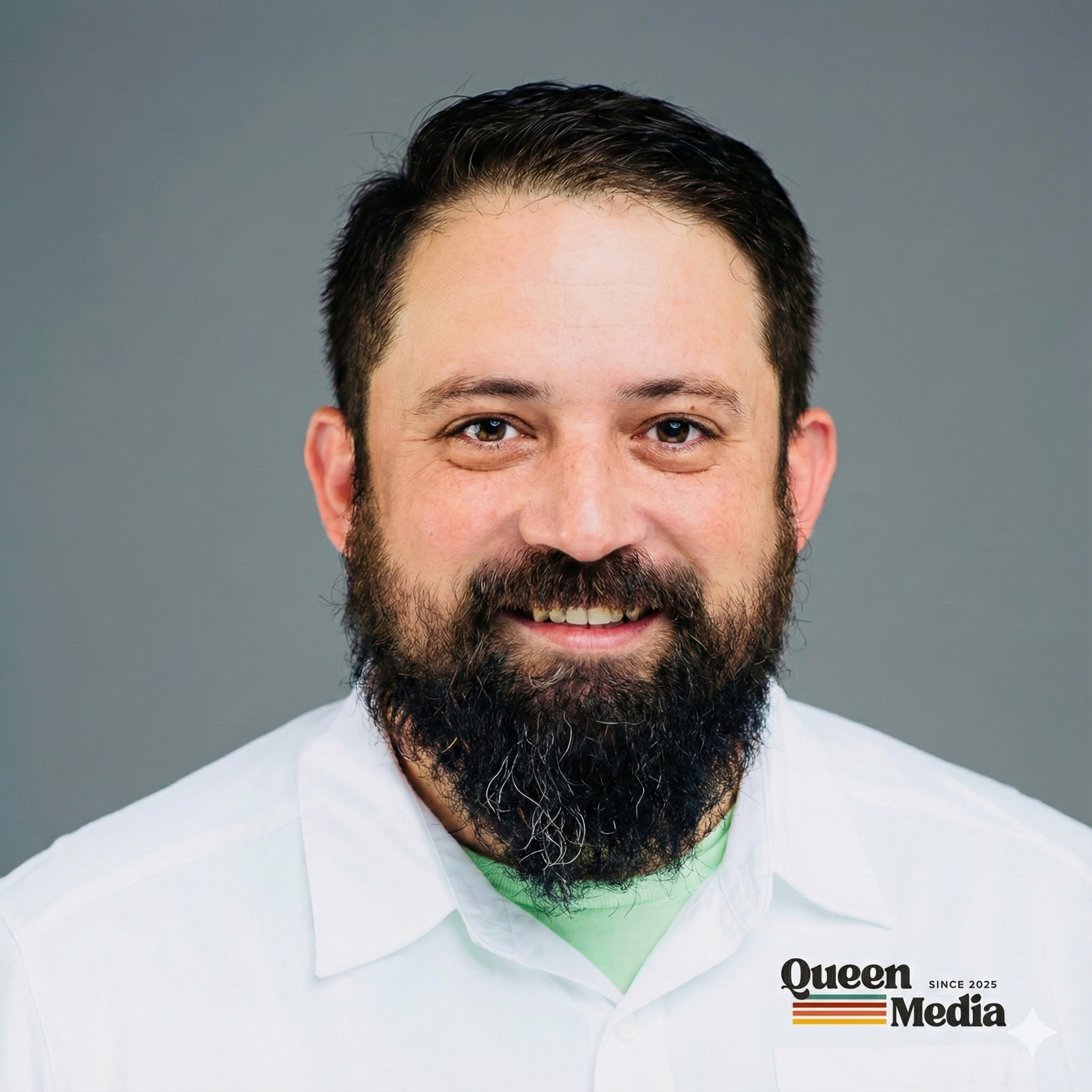 Headshot of a smiling man with dark hair, a beard, wearing a white shirt, against a gray background. The logo 'Queen Media' is visible in the bottom right corner.