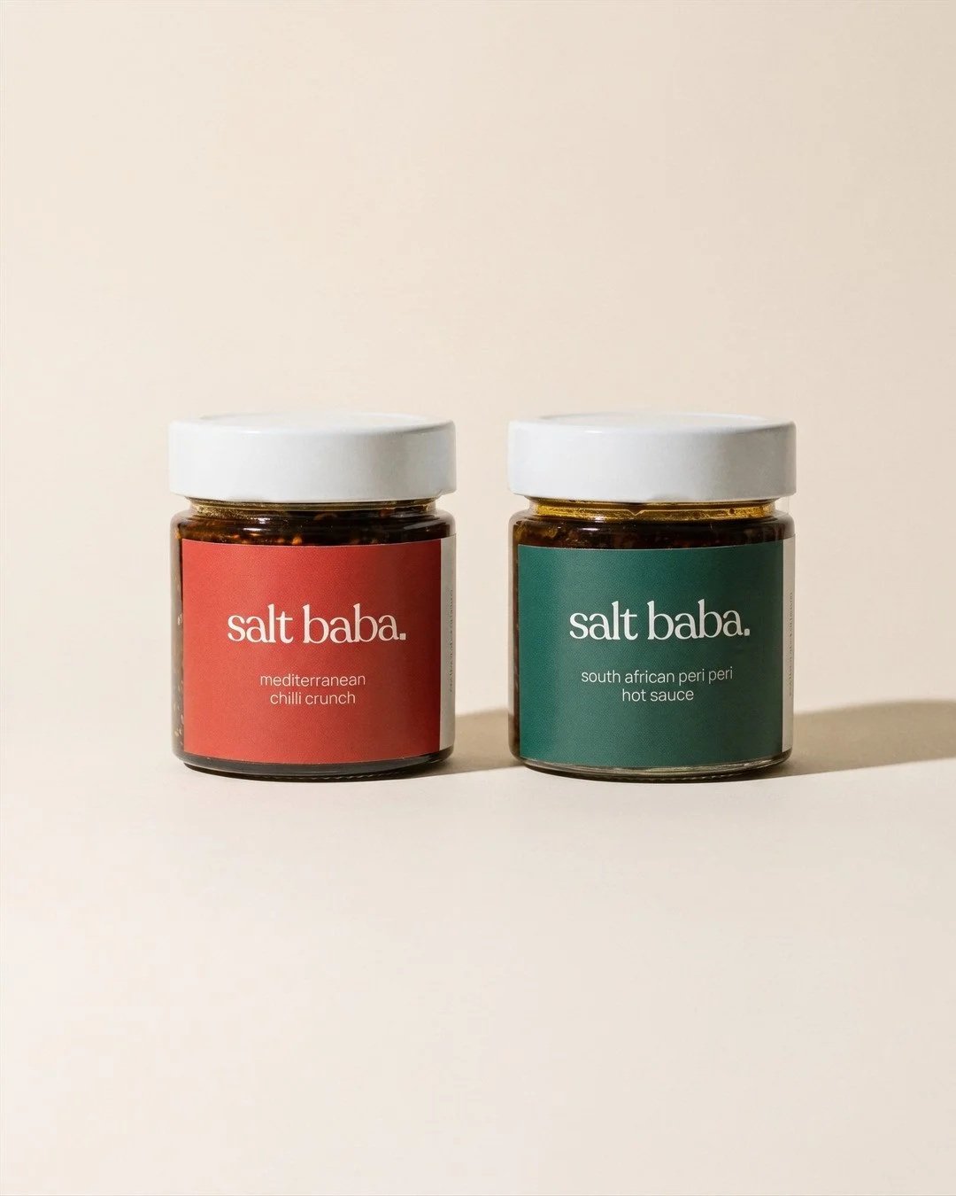 Two Salt Baba jars of Mediterranean chilli crunch and South African peri peri hot sauce