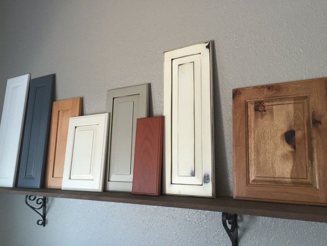Multiple cabinet or door front samples in various colors and finishes displayed on a wall shelf.
