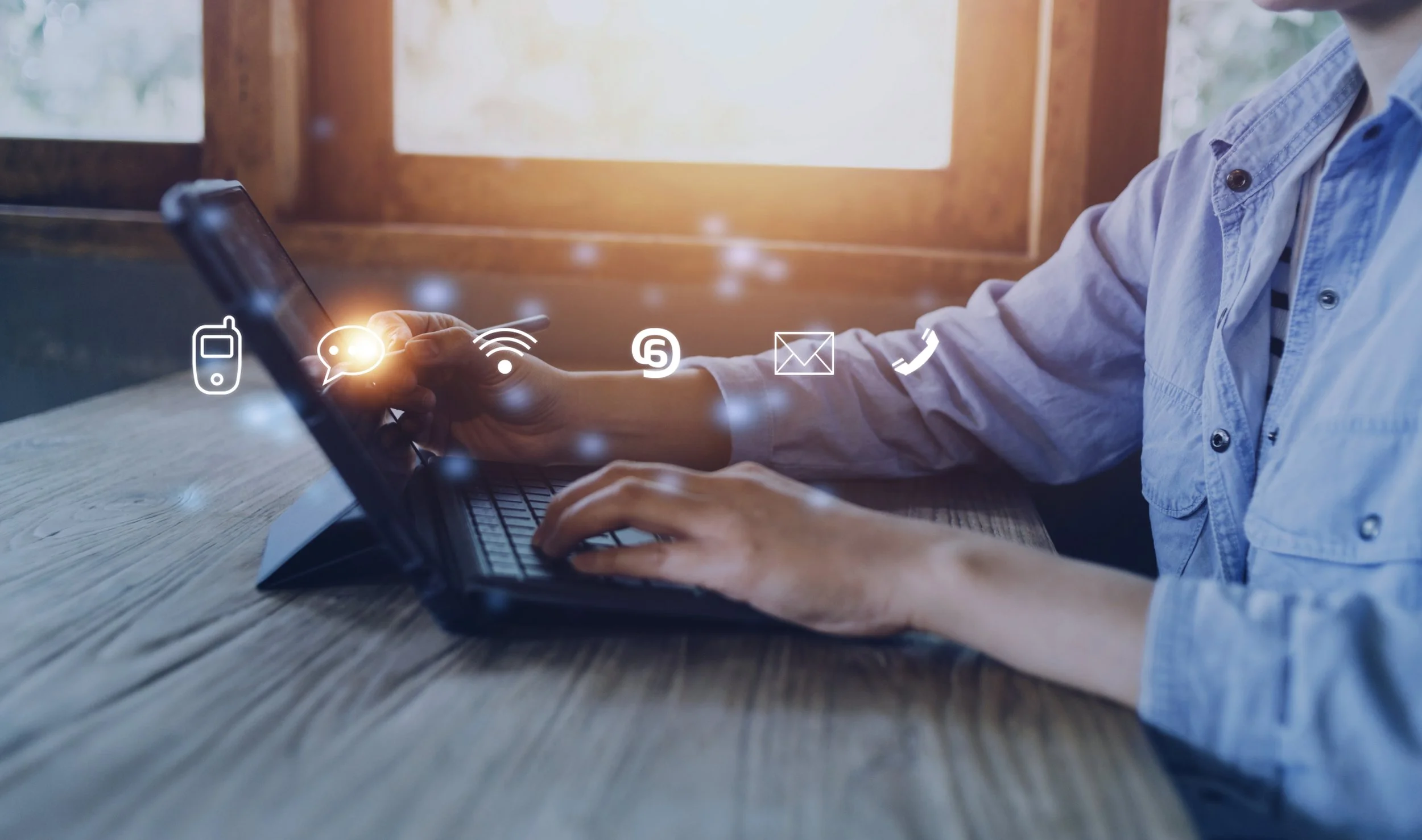 Person using smartphone and laptop with floating app icons including message, Wi-Fi, call, and email on the screen.