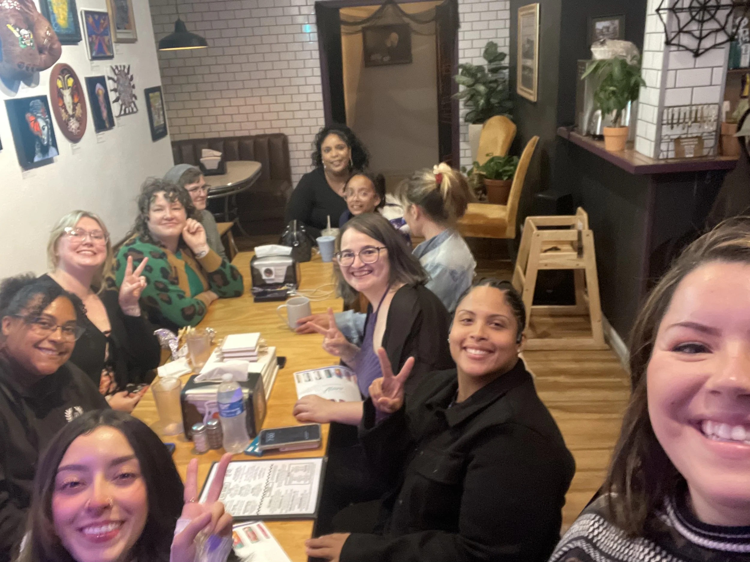 Group of women sitting around a dining table in a restaurant, smiling and posing for the photo.