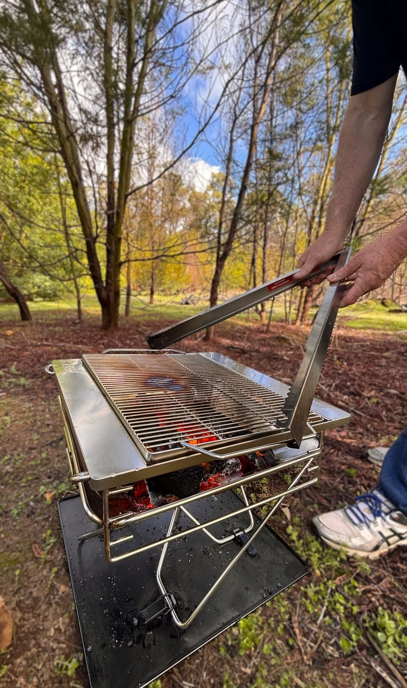 Tongs for Tossers lifting grill from fire pit on Fathers Day