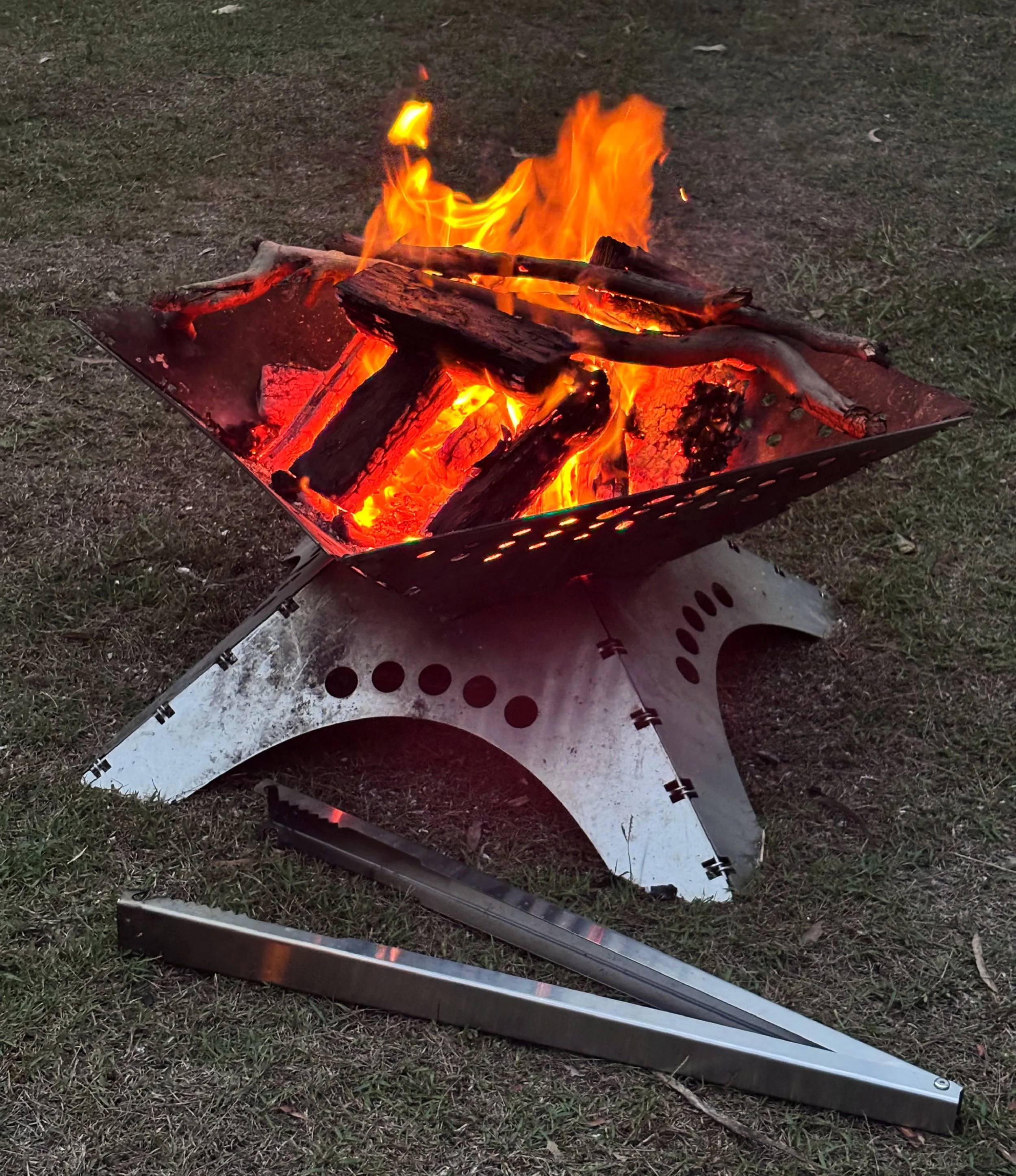 Tongs for Tossers near some firewood, with a Stubby Cooler and a Tongs for Tossers Hat