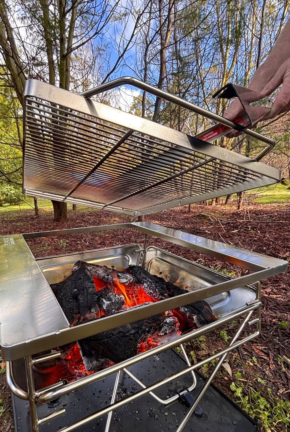 Hot fire pit grill being lifted by Tongs for Tossers