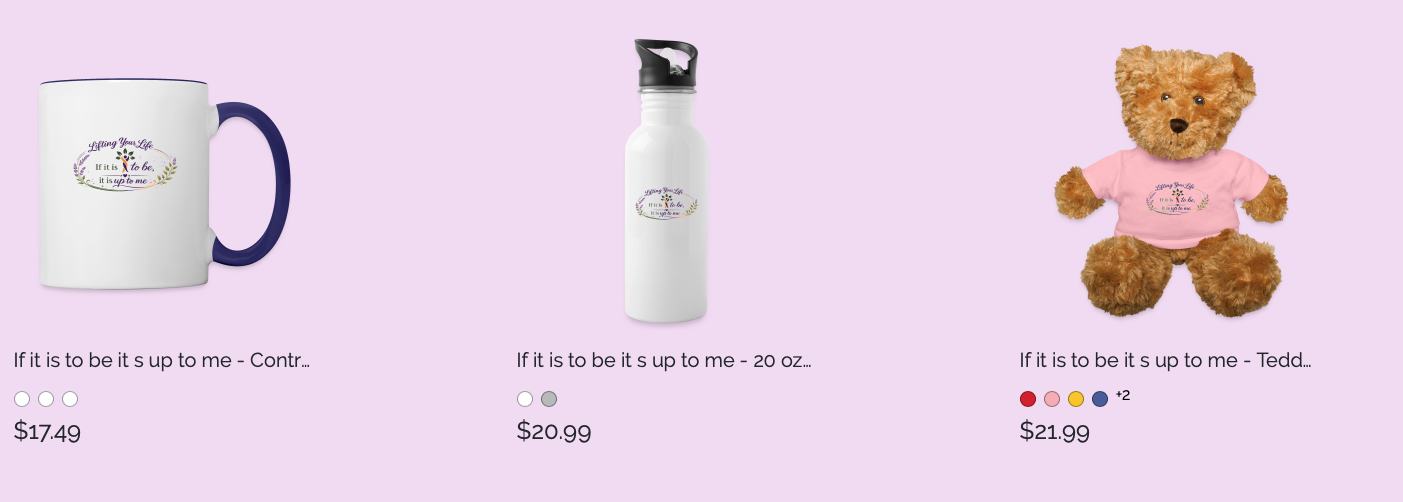 A white mug with a navy handle and a white water bottle, both featuring a colorful quote and floral design, and a plush teddy bear wearing a pink T-shirt with the same quote against a light purple background.