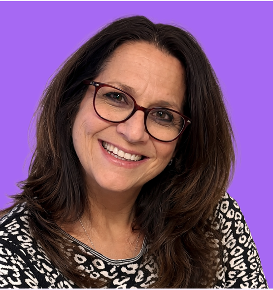 Woman with long brown hair, glasses, and a patterned black and white top smiling against a purple background.