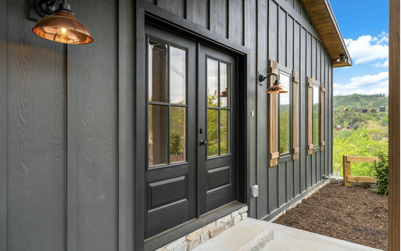 Modern cabin front entry with black siding, glass doors, and natural wood accents in Gatlinburg, Tennessee.