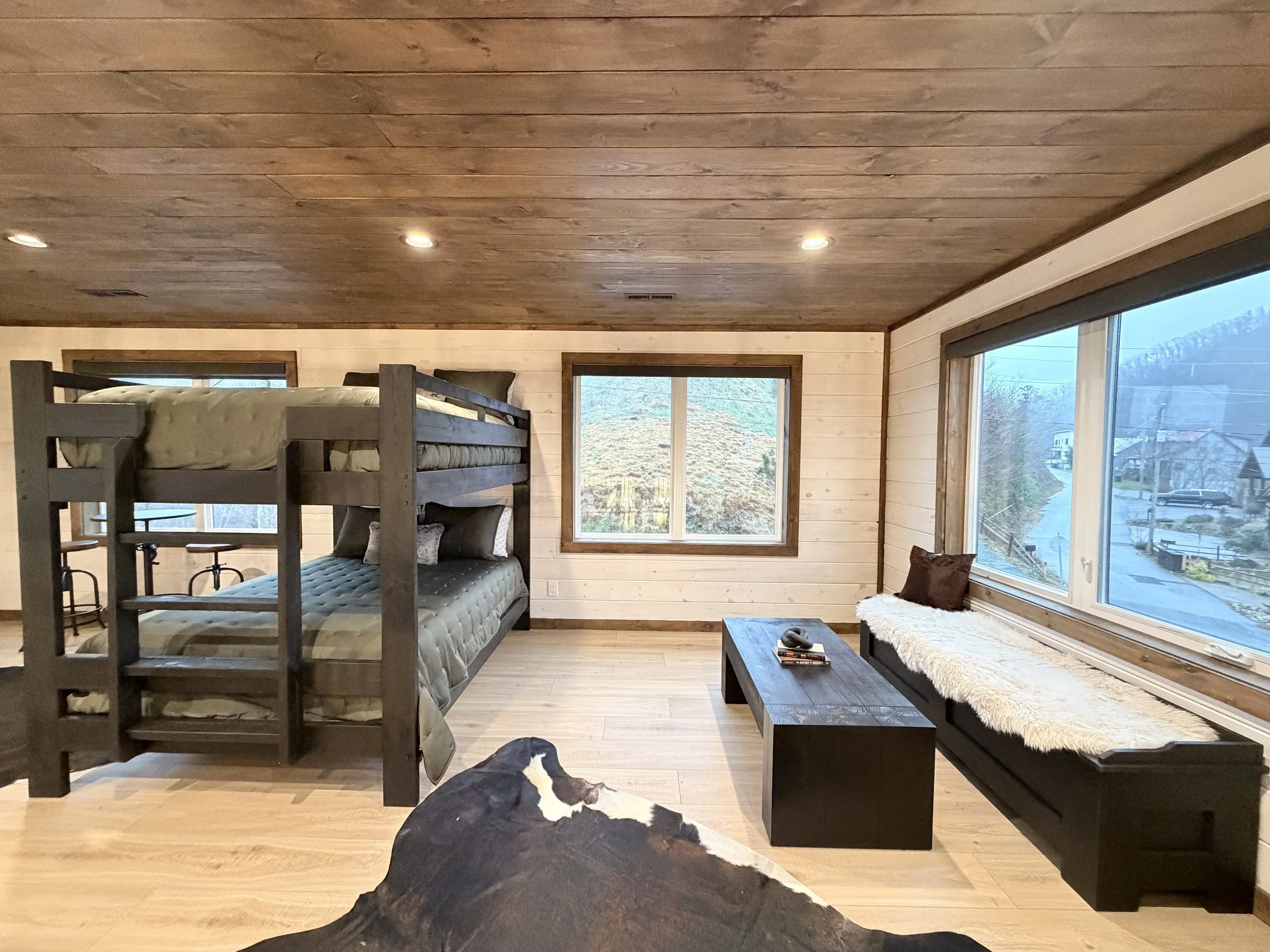 Rustic modern bunk room interior in a Smoky Mountain cabin featuring custom wood finishes, built-in bunk beds, and cozy seating for short-term rental design.