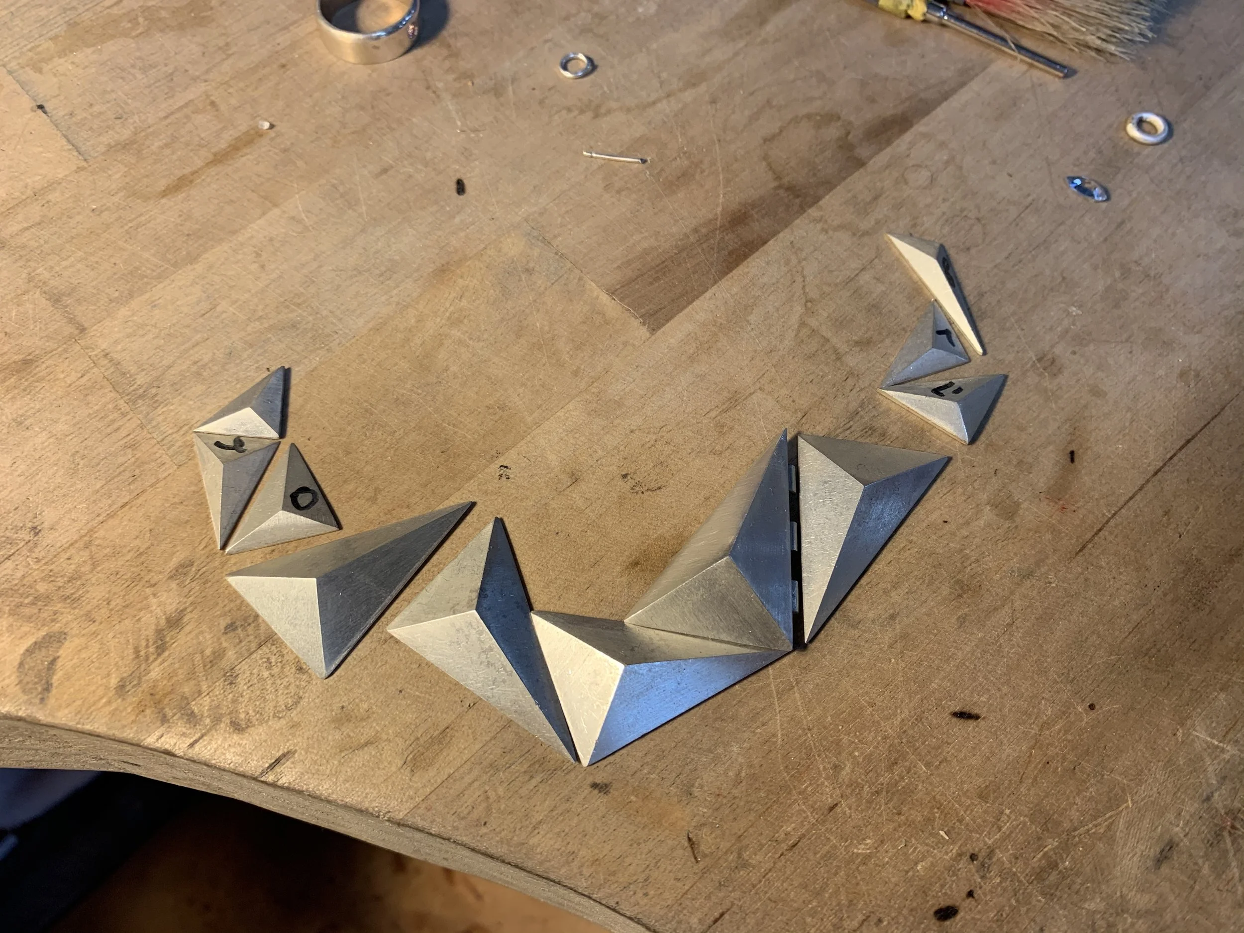 Poker chips and metal pyramid-shaped objects arranged in a circle on a wooden surface.