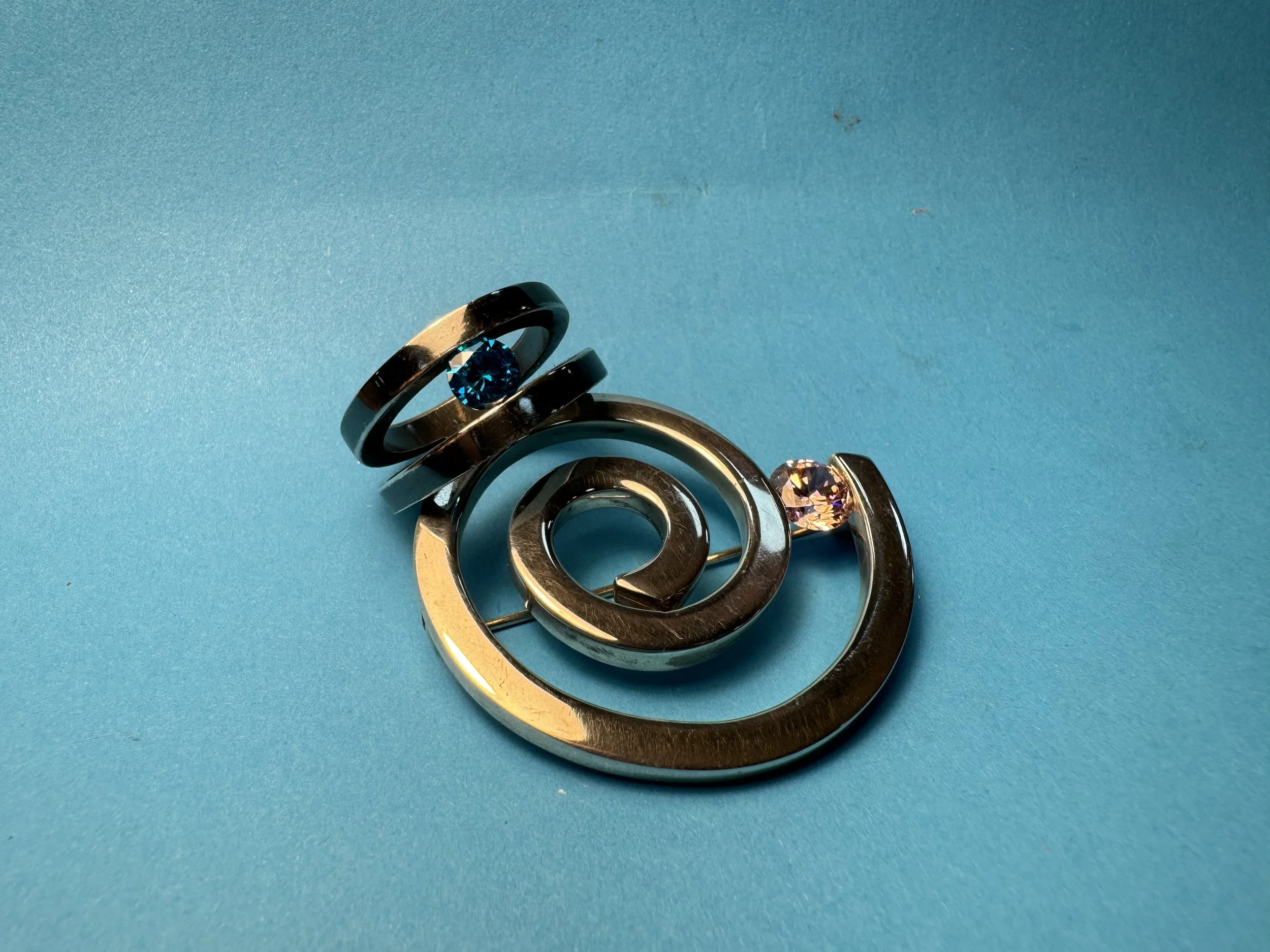 A collection of metallic rings with gemstones on a blue background.