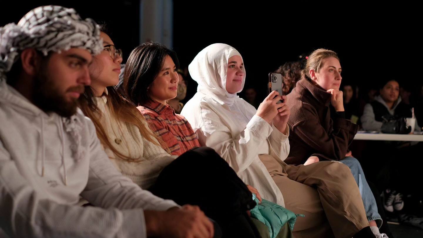 Audience sitting in row at a poetry slam event.