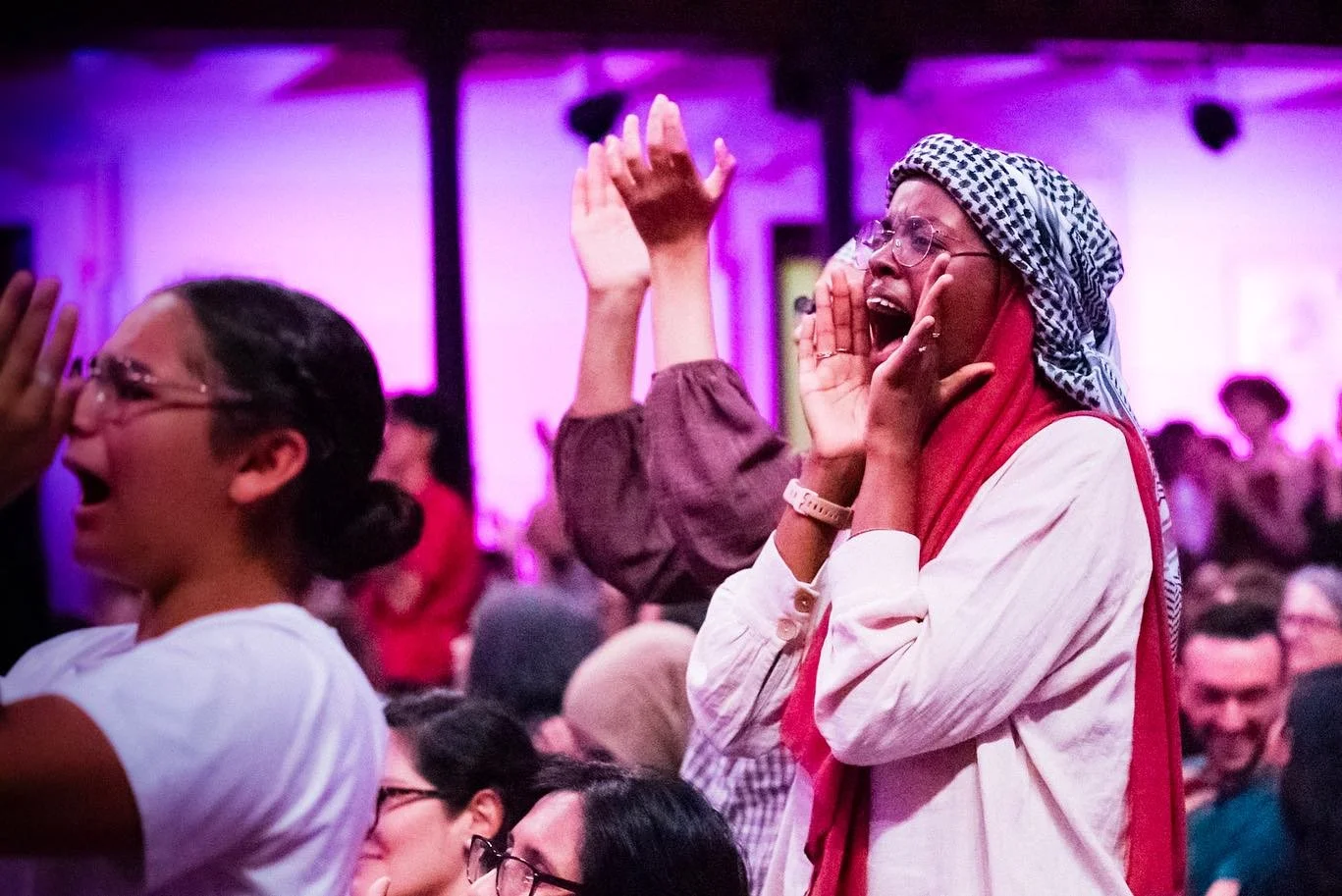 People at an indoor event cheering for the performer on stage.