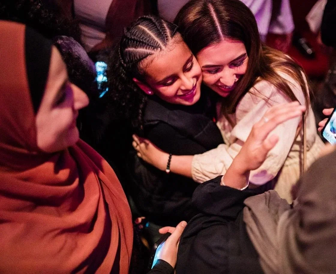 A group of women smiling and hugging each other.