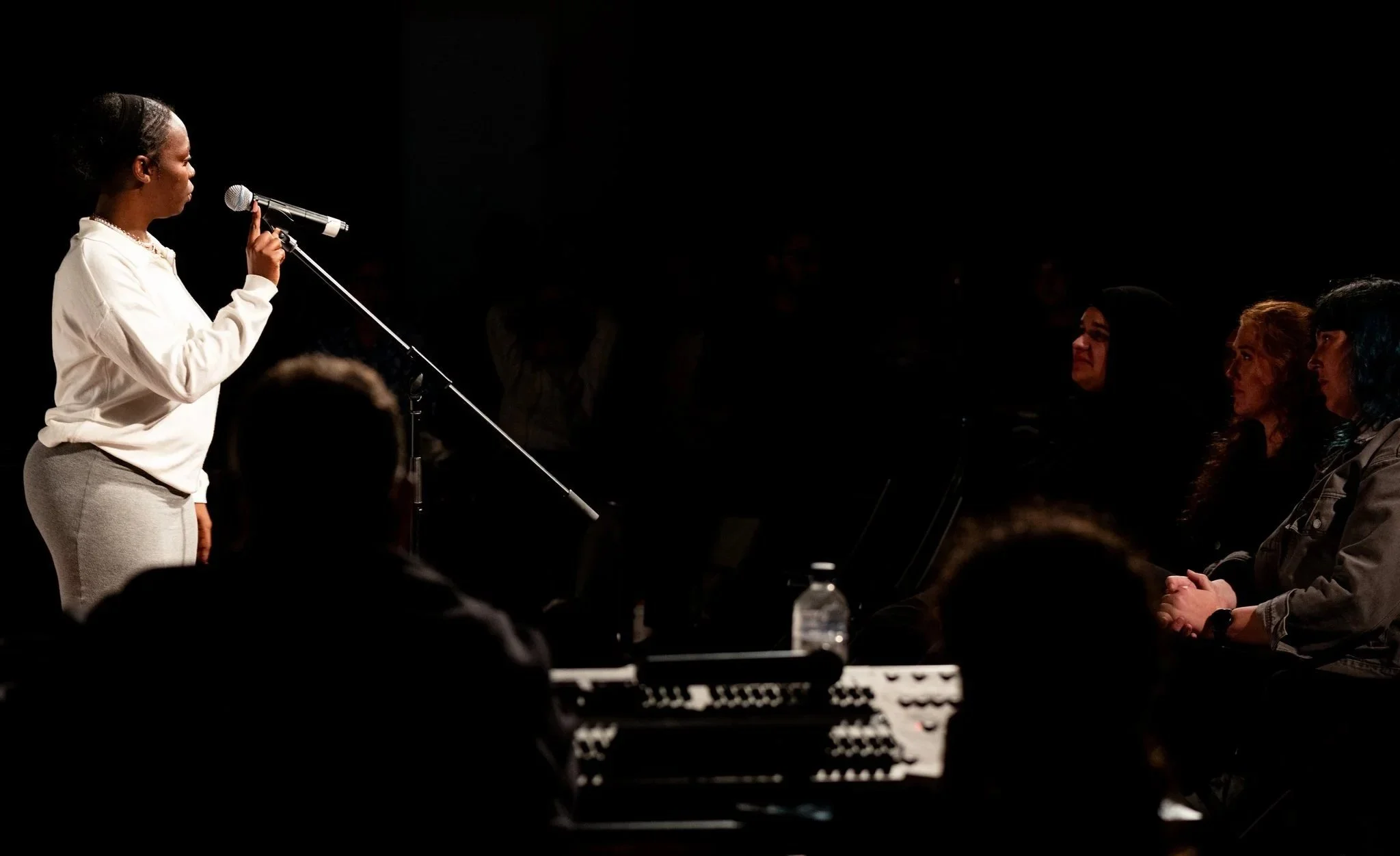A woman performing to an audience at a poetry slam event.