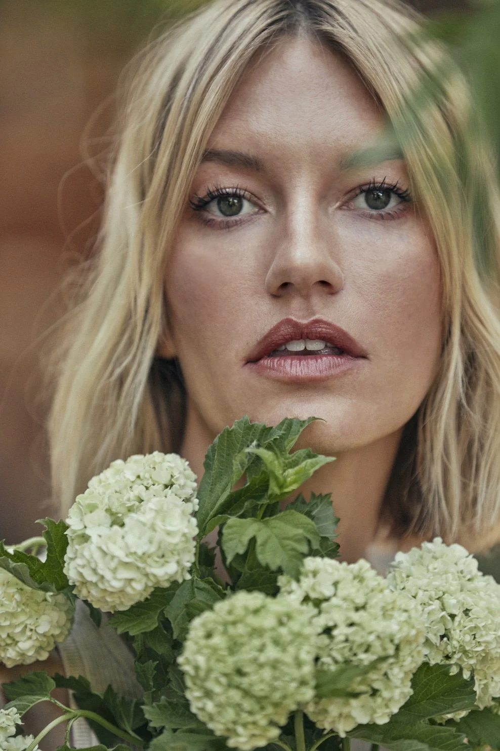 A woman with blonde hair holding a bouquet of white hydrangea flowers.