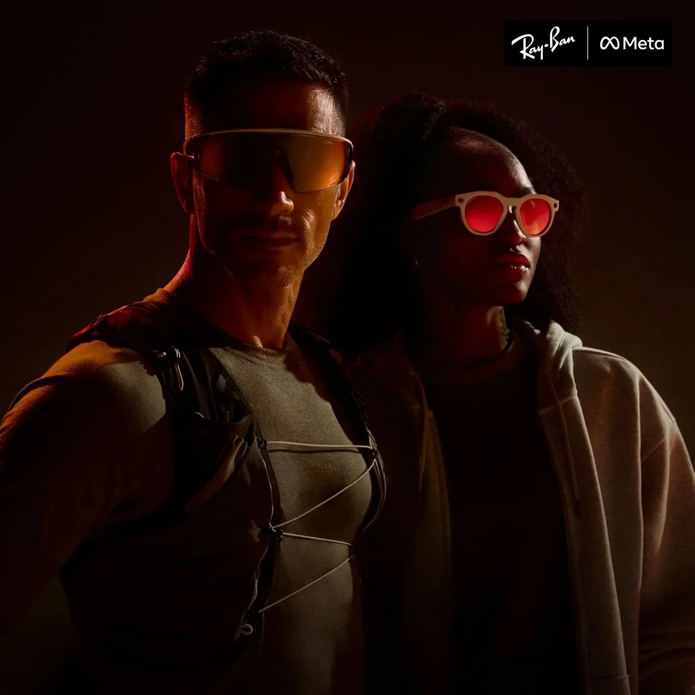 Two individuals wearing sunglasses, one with a backpack, standing in front of a dark background with a logo for Ray-Ban and Meta in the top right corner.