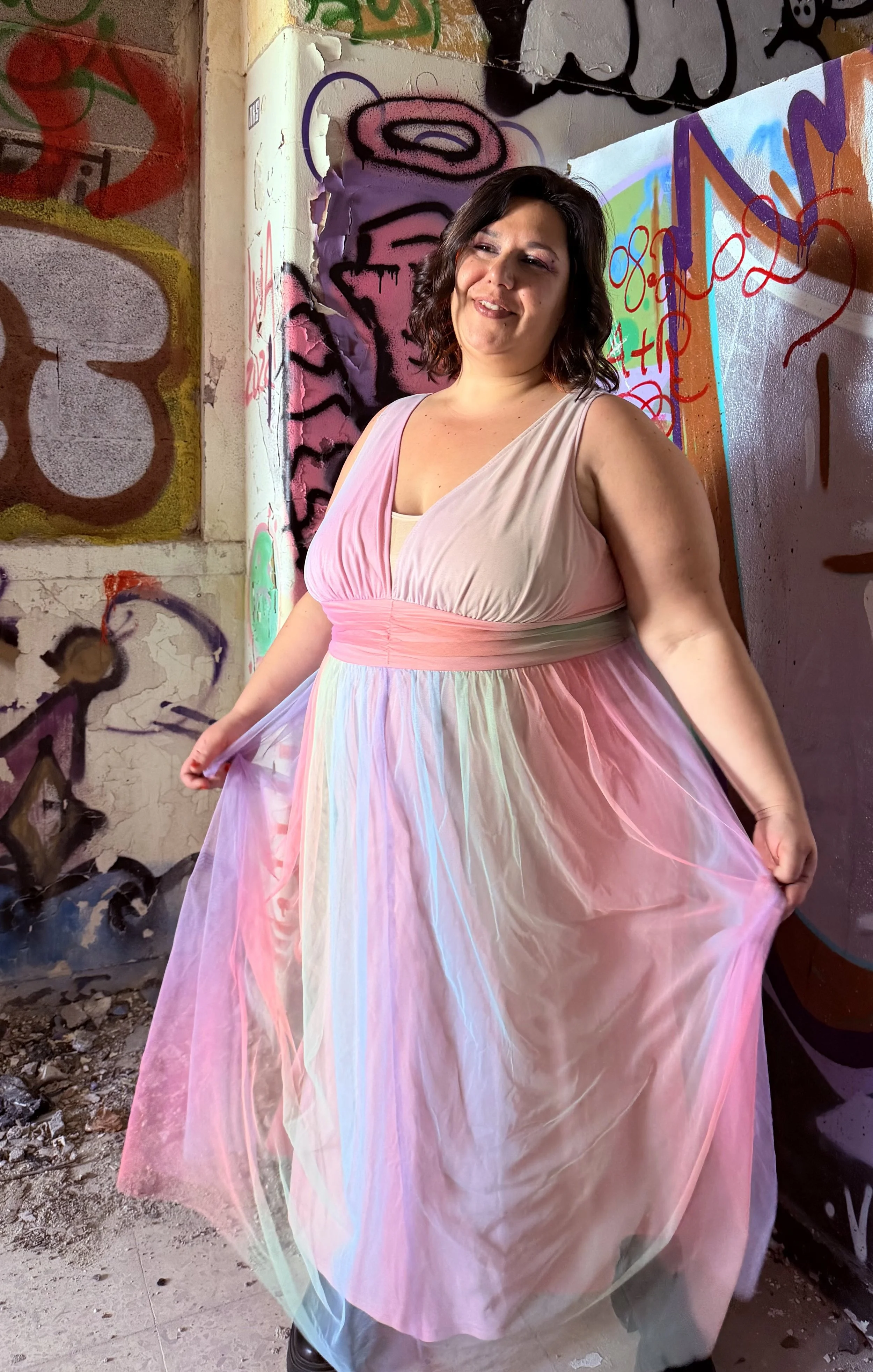 Teresa Ribeiro in a pastel dress among colourful, graffiti-covered ruins.