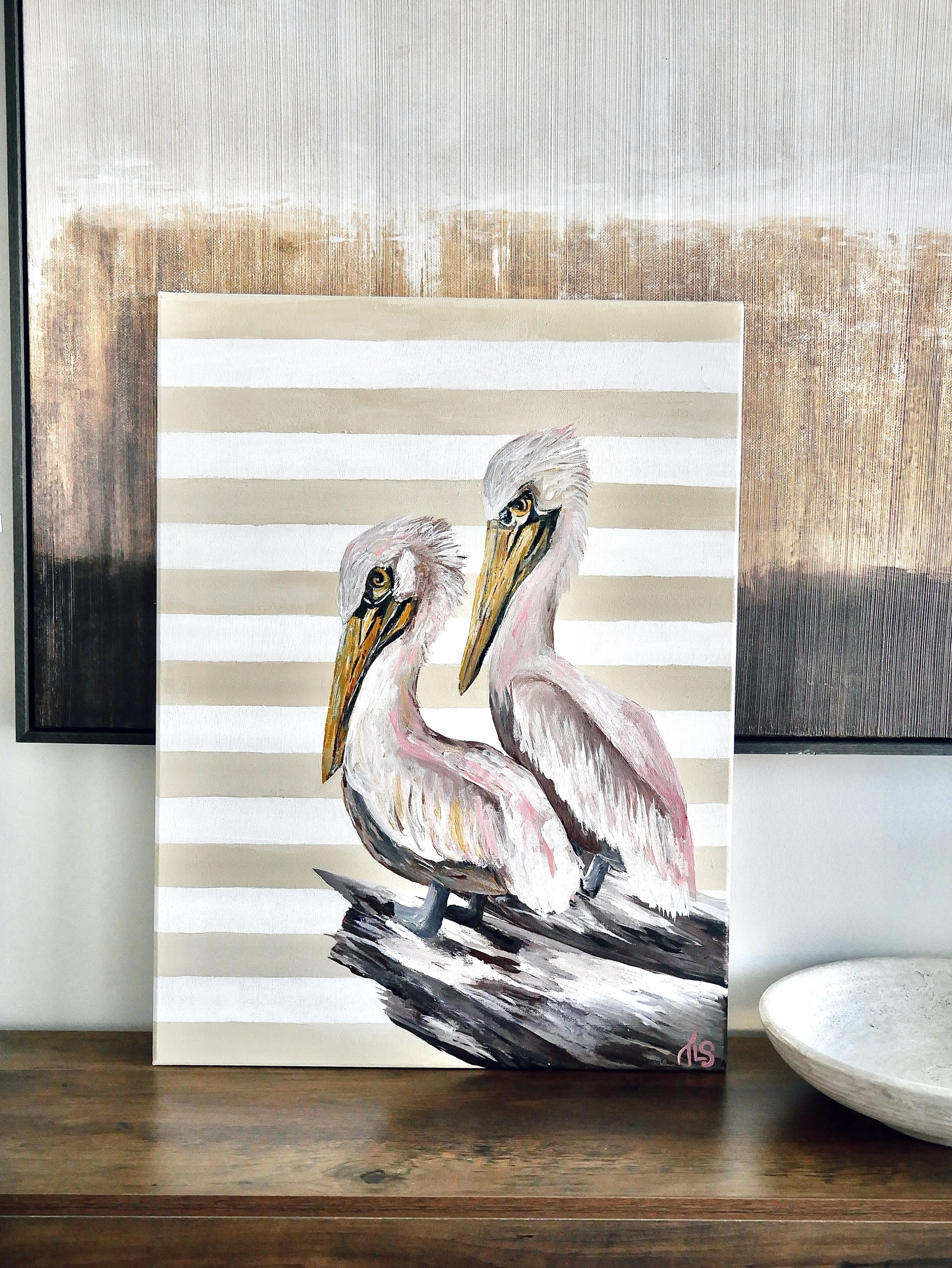 Painting of two pelicans with pink and white feathers, standing on a log, against a background of beige and white horizontal stripes.
