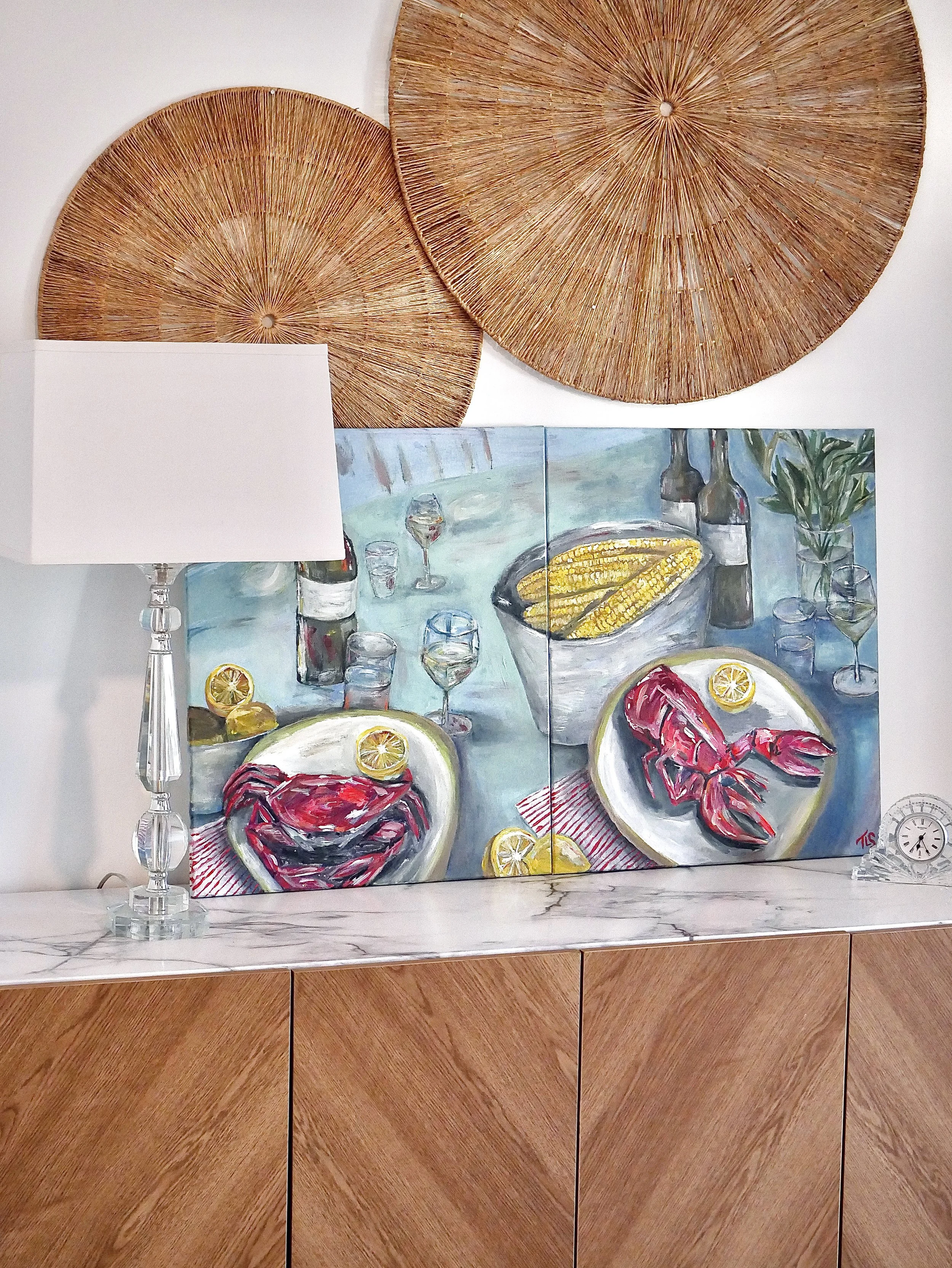 A colorful painting of two lobsters on plates with lemon slices, bottles of wine, glasses, and a bowl of corn on a table, against a backdrop of a dining scene.