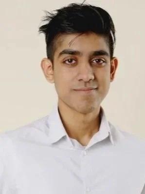 Nick is a brown man with short black hair. He is facing the camera with a small smile. He is wearing a white button down shirt.