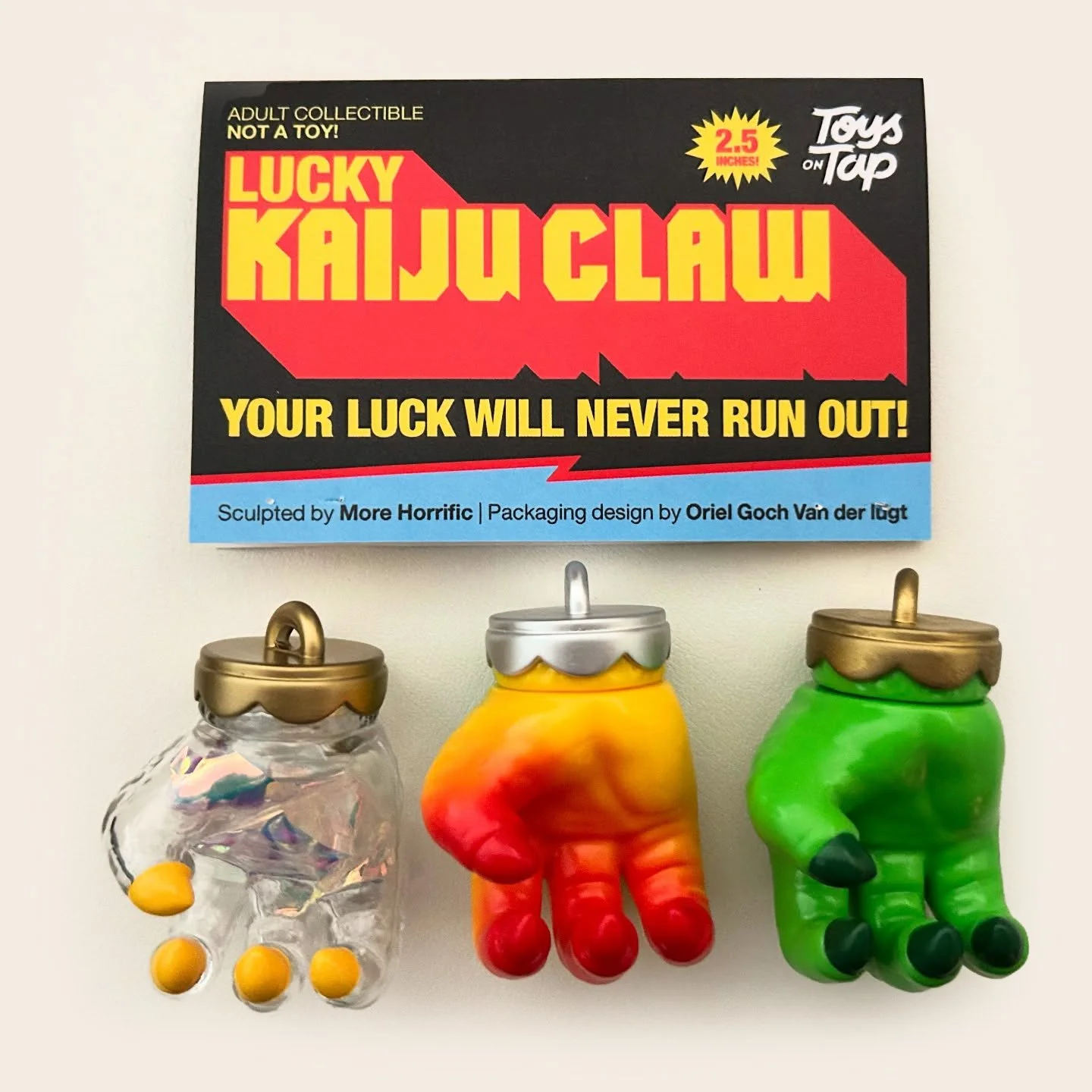 Colorful hand-shaped figurines resembling different colored candies with gold and silver caps, part of a Lucky Kaiju Claw game on a white surface.