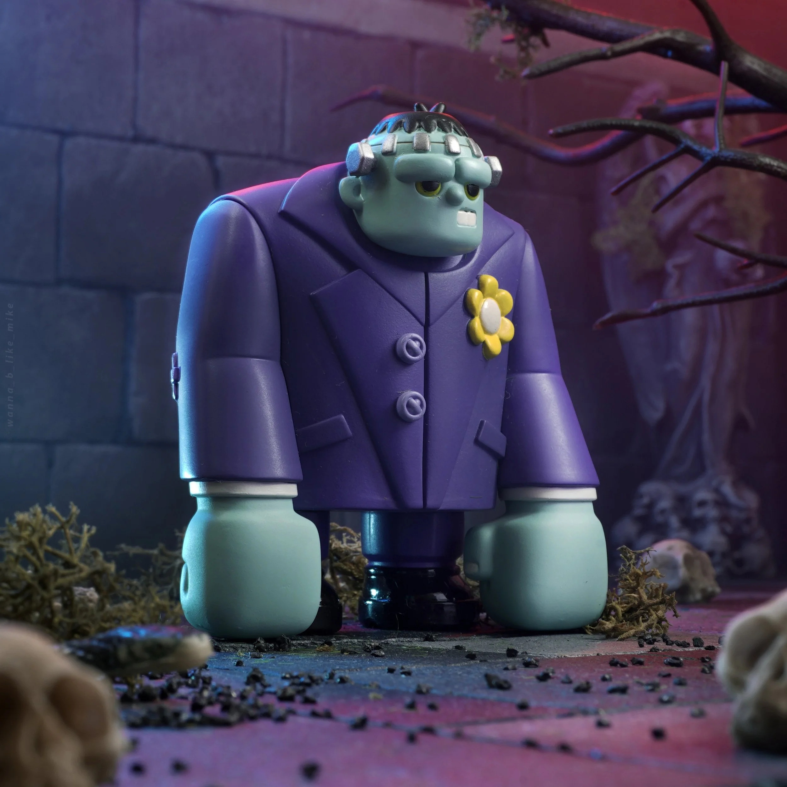 A close-up shot of a cartoon character resembling Frankenstein's monster, standing on a colorful, textured surface, with a dark brick wall and twisted black branches in the background.