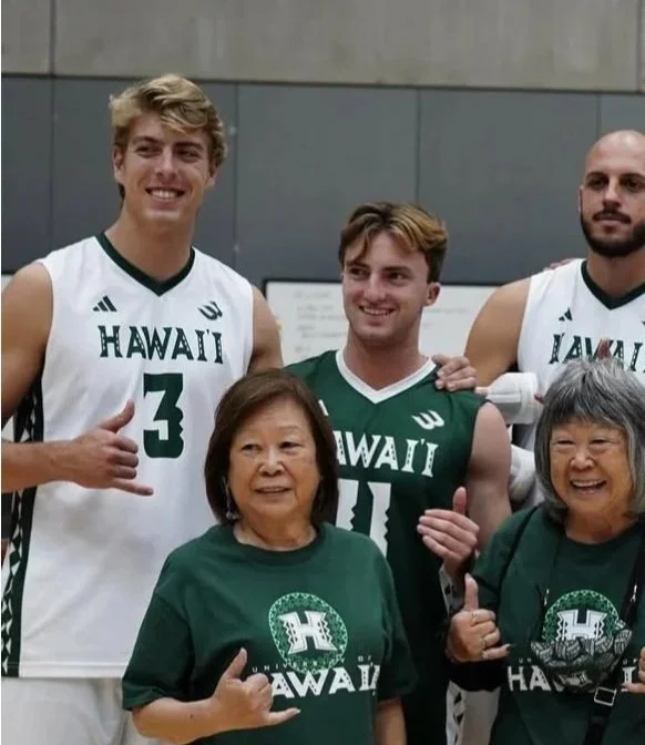 Three male college basketball players in Hawaii jerseys and two women in Hawaii T-shirts, all smiling and giving thumbs-up.