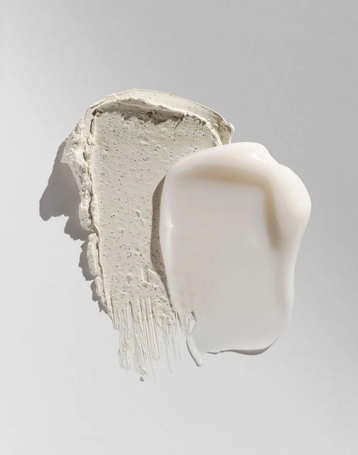 Cream and white textured skincare products on a white surface
