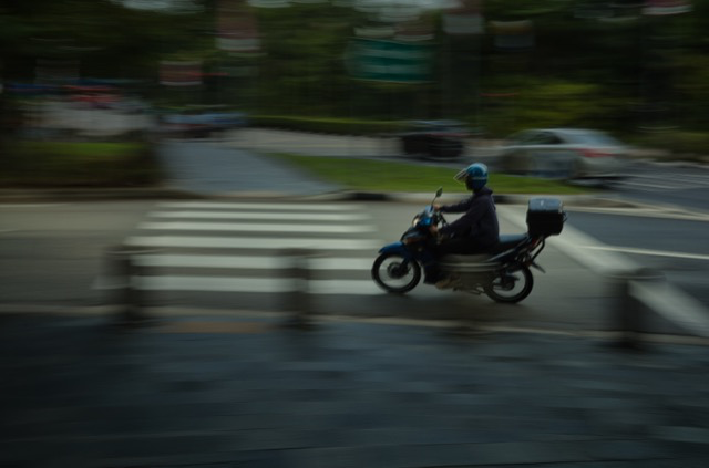 Motorcycle rider wearing a helmet traveling on the road with a blurred background.