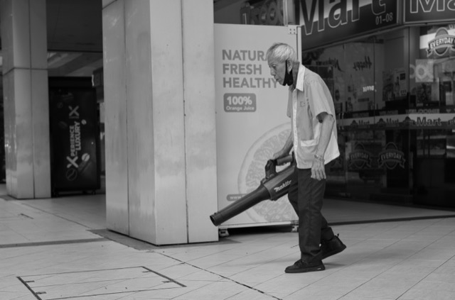 Man vacuuming the floor inside a shopping mall or grocery store