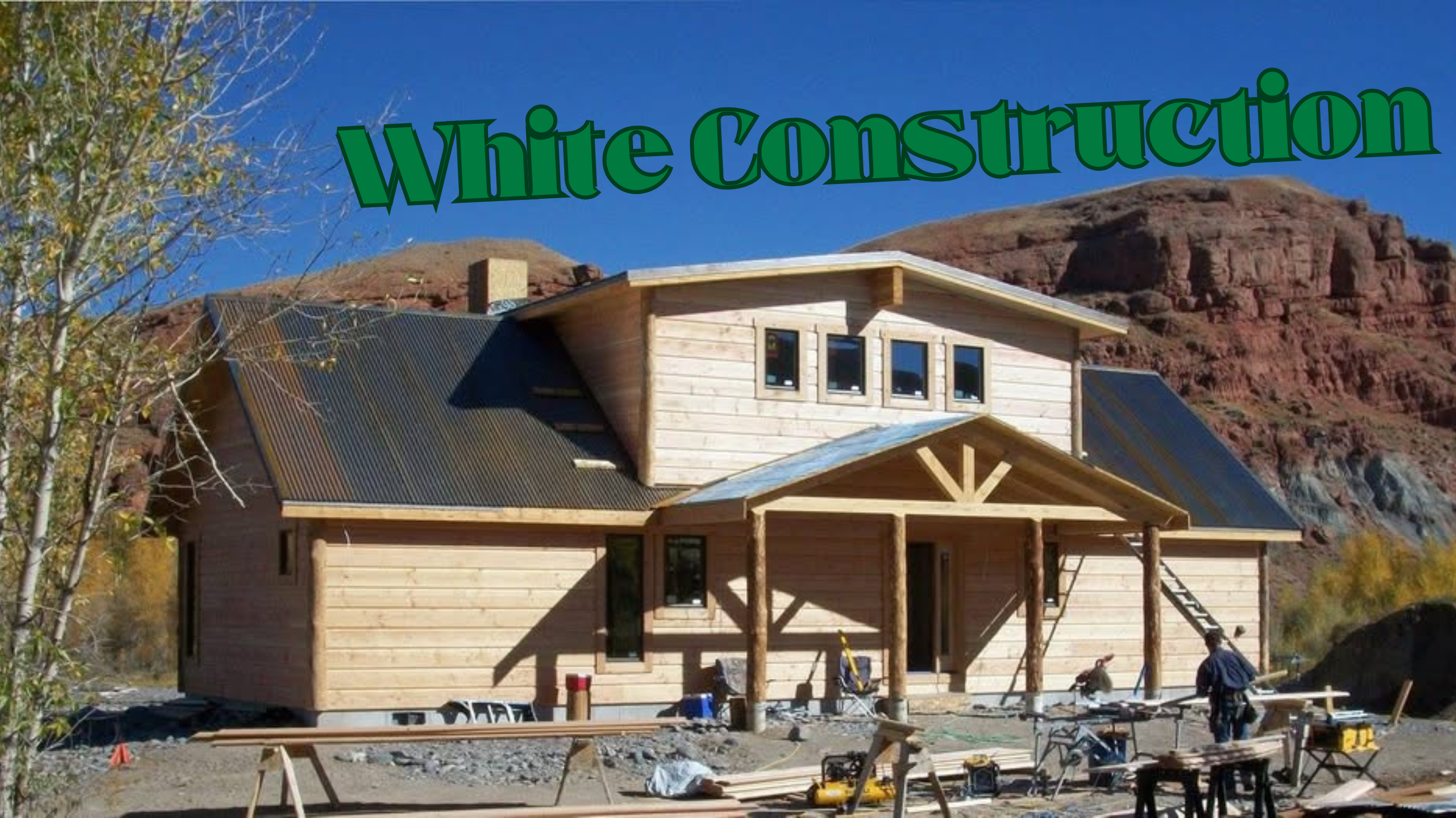 A house under construction with a wooden exterior, a porch, and a metal roof, situated in a desert landscape with mountains in the background, and workers and construction tools in the foreground.