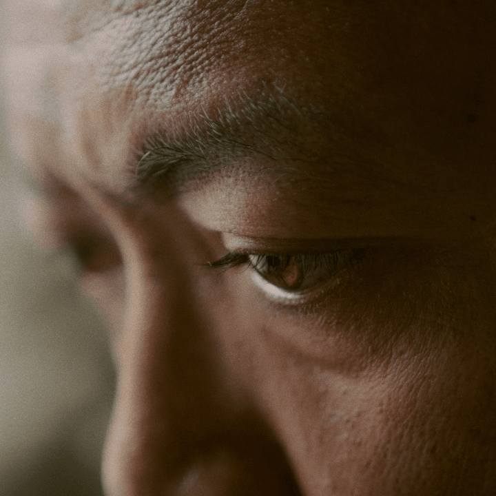 Close-up of a person's eye looking down, showing detailed skin texture and eyelash.