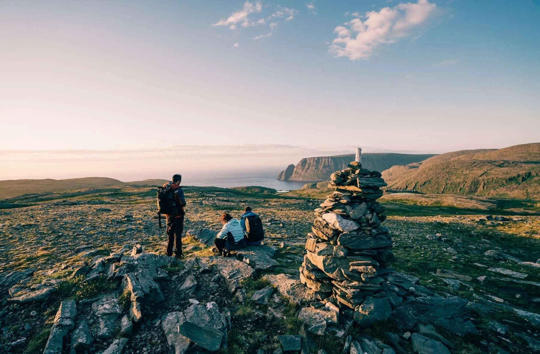 tre personer som er på strategisamling og har pause der de går tur i fjellet og ser på utiskten