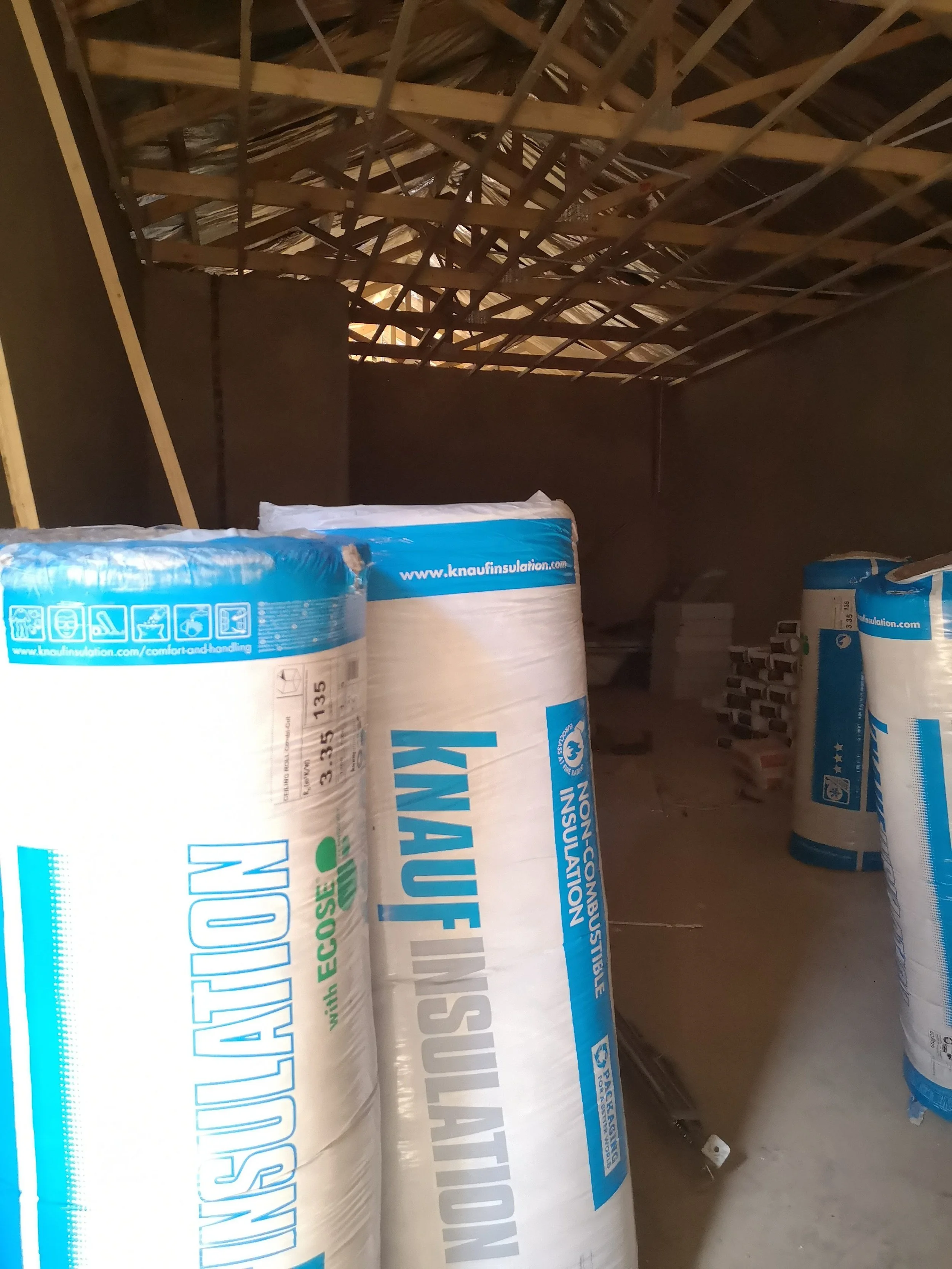 Insulation rolls stacked in an attic space.