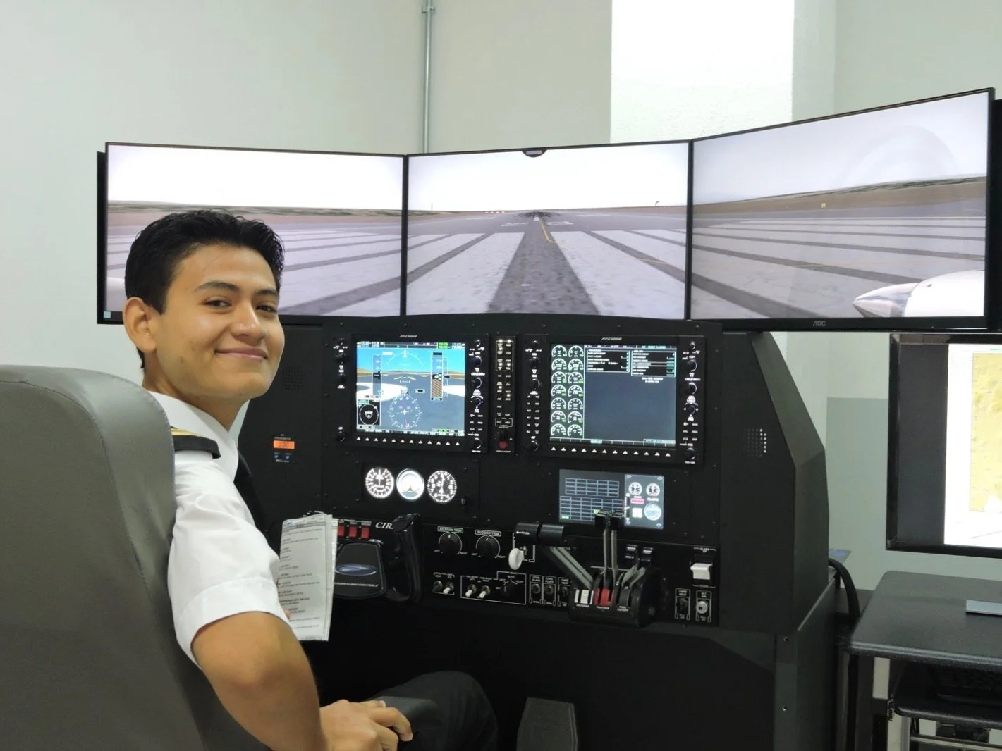 Joven en cabina de simulador de vuelo con tres pantallas mostrando una pista de aterrizaje y panel de control con instrumentos y pantallas digitales.