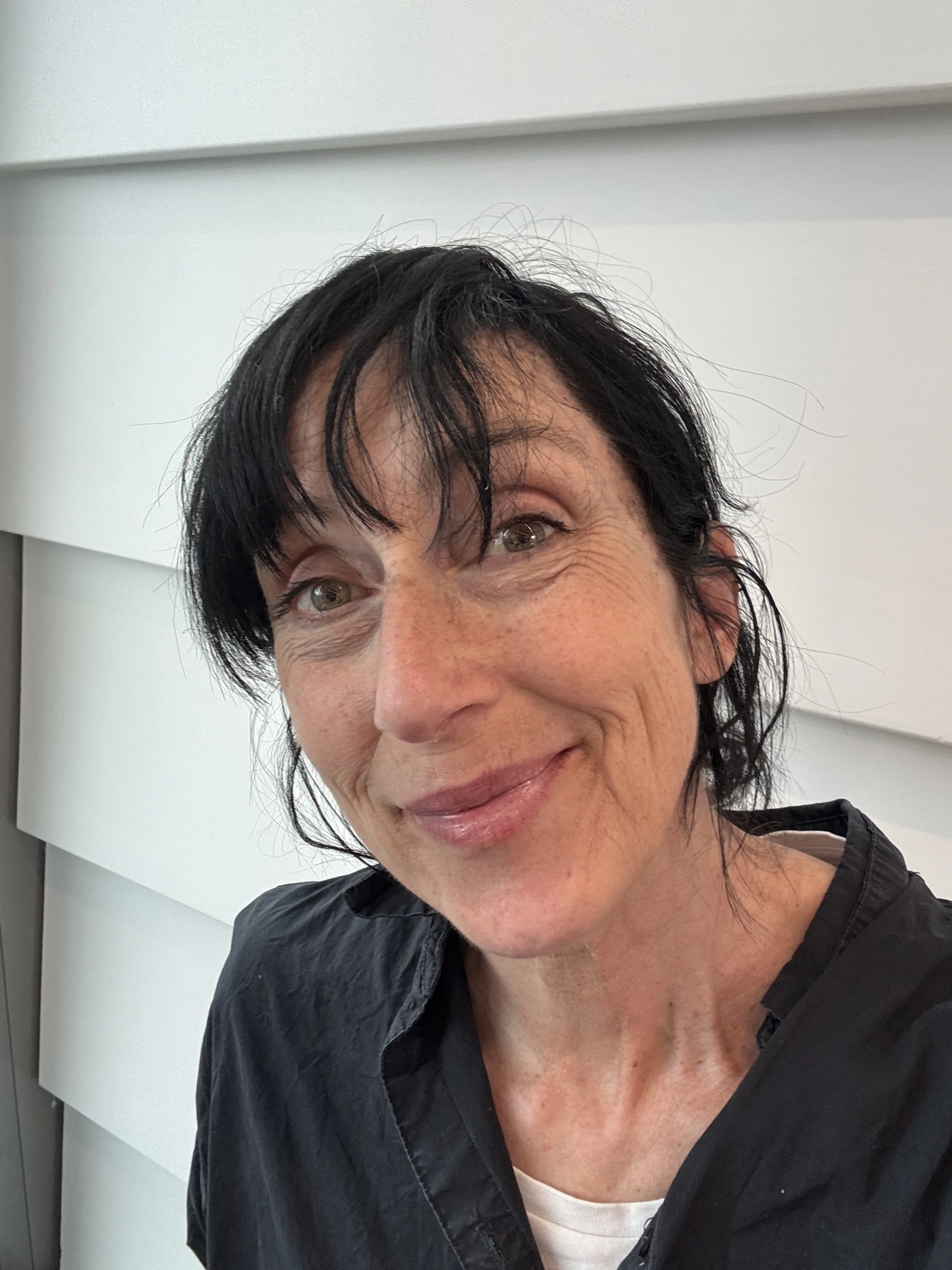 Åsa Asp porträtt mot en vitmålad trävägg.