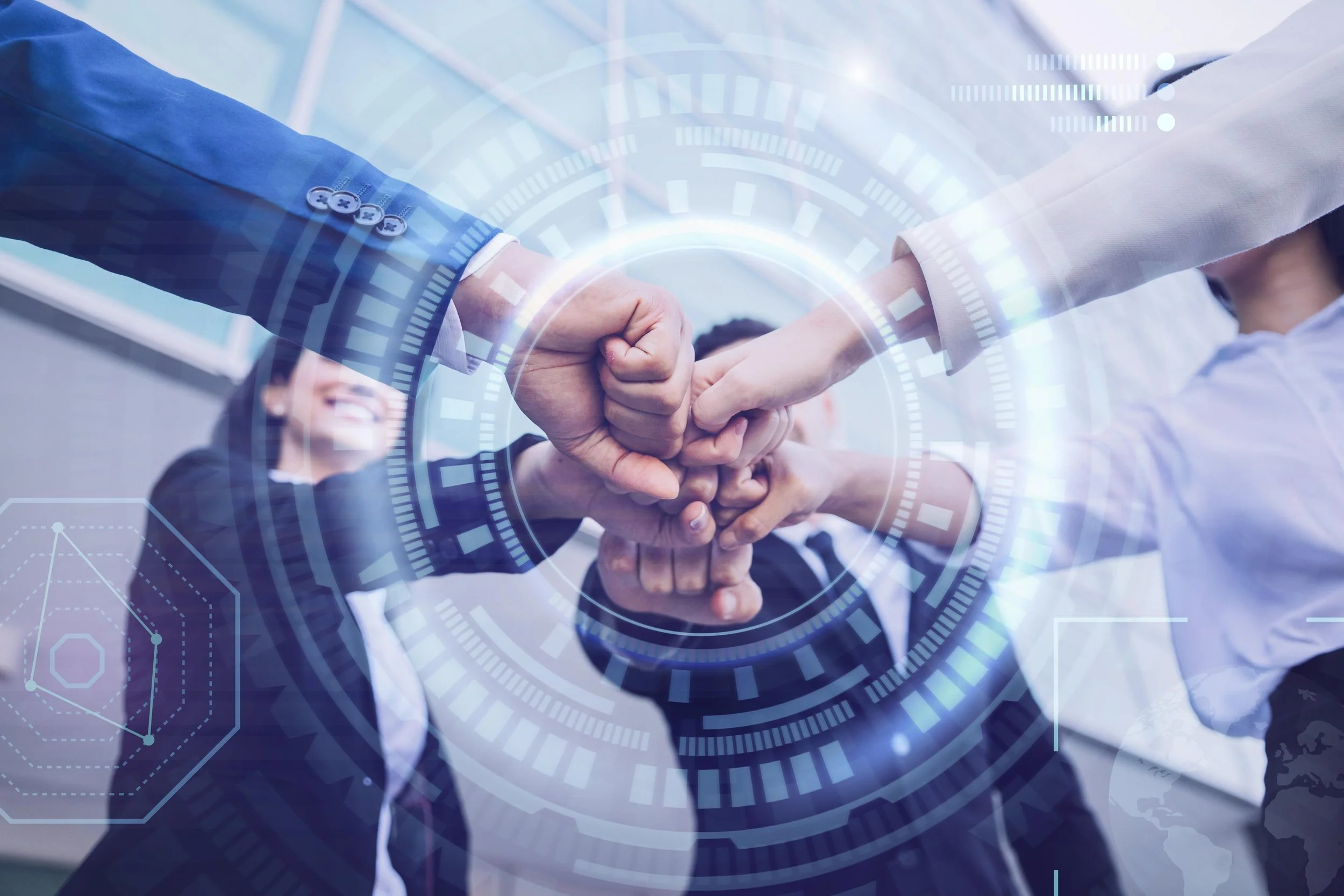 Multiple people in business attire join hands in a group fist bump, with a digital overlay of circular and geometric graphics.