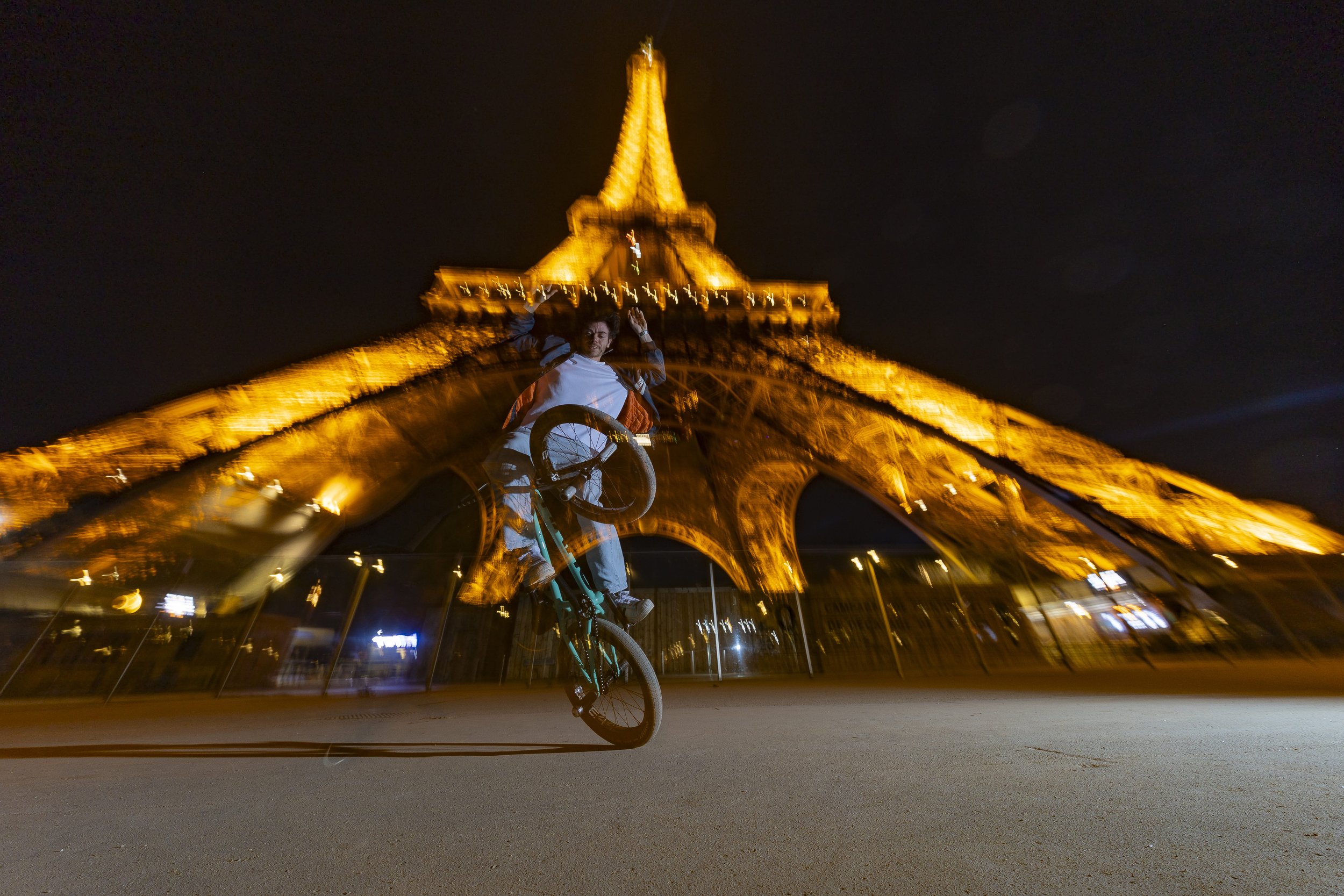 rider BMX en trick devant la tour Eiffel de nuit